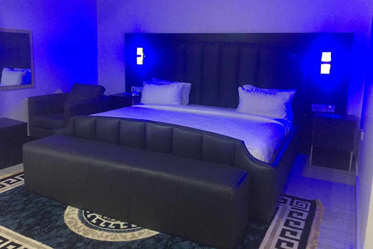 Ein modernes Schlafzimmer mit einem großen Bett, einer schwarzen Lederbank und einem gemusterten Teppich.