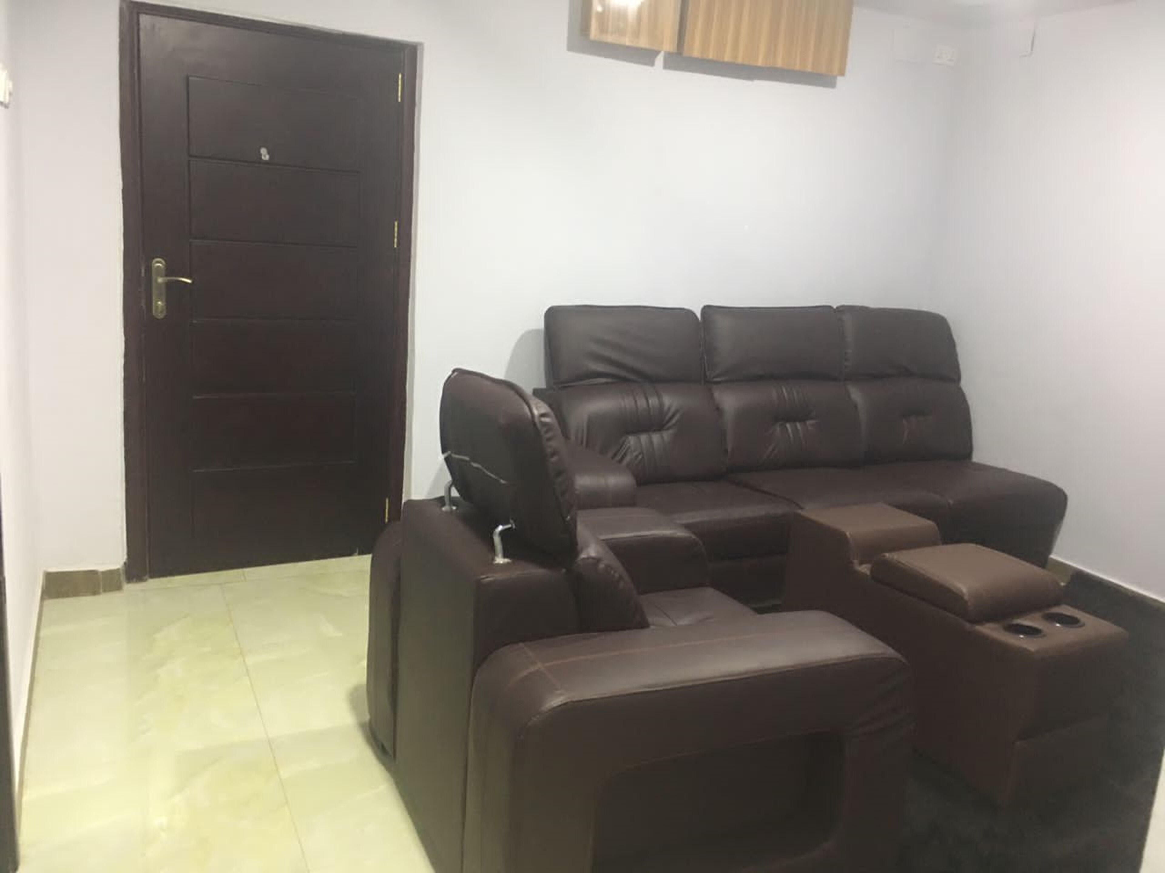 A living room with a dark brown leather sofa, a small table, and a closed door.