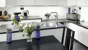 Een moderne keuken met witte kastjes, een zwart aanrecht en een spoelbak. Er staan vazen met bloemen op het aanrecht.