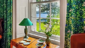 Een kamer met een houten tafel, een groene lamp en een bloemenvaas.