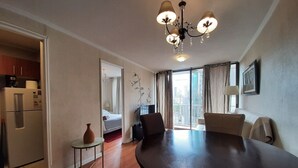 A dining area with a large table, chairs, a small side table, and a refrigerator. - Living Pastene  (Santiago)
