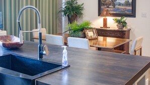 A modern kitchen with a dark countertop, a built-in sink, a wooden bowl, and a water dispenser. - Peaceful Pastures near PK Lake (Graham)