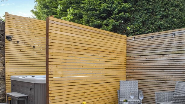Un área de patio con un jacuzzi, sillas de mimbre y plantas en macetas.