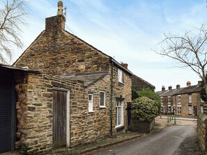 Un bâtiment en pierre avec un toit en pente, une porte en bois et une petite fenêtre.