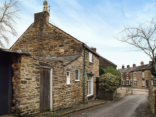 A stone building with a sloped roof, a wooden door, and a small window.