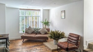 Una sala de estar moderna con un sofá y una butaca de cuero marrón, junto con una mesa de centro de madera.