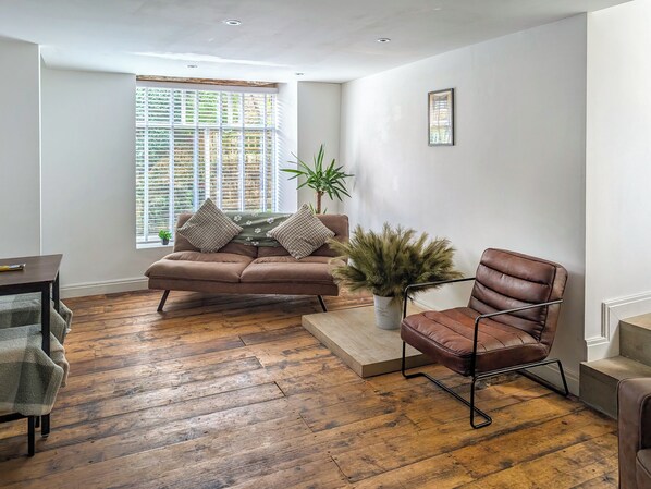 Una sala de estar moderna con un sofá y una butaca de cuero marrón, junto con una mesa de centro de madera.