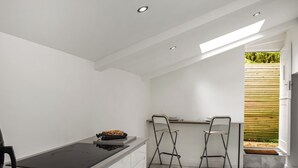 Una cocina compacta con una isla central, dos taburetes de bar y vistas al exterior.