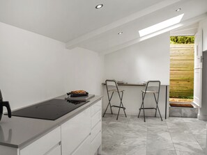 Una cocina compacta con una isla central, dos taburetes de bar y vistas al exterior.