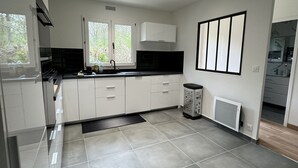 Una cocina moderna con armarios blancos, encimera negra y suelo de baldosas.