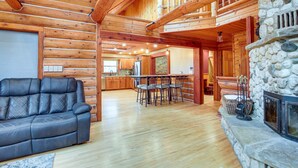 L’intérieur d’une cabane en rondins comprend un salon, un coin repas et une cheminée en pierre.
