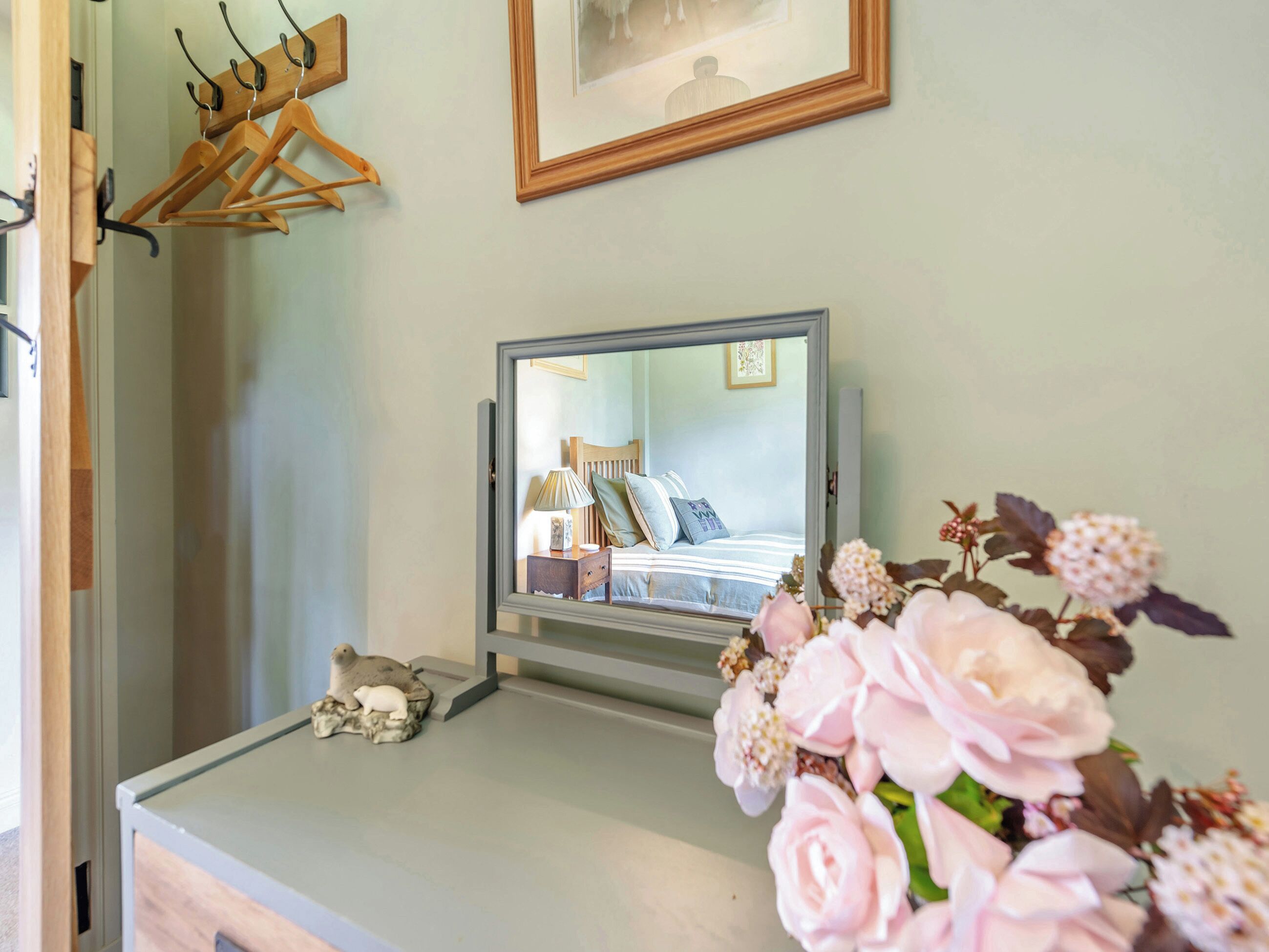 A bedroom with a bed, bedside table, lamp, and a mirror reflecting the room.