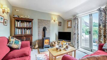 A living room with a fireplace, a bookshelf, a television, and a view of the outdoors.