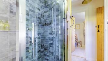 A bathroom with a glass-enclosed shower, a white bathtub, and a wooden door.