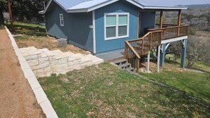Una casita de una sola planta con fachada azul y una terraza de madera.