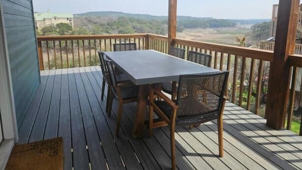 Una terraza techada al aire libre con una mesa y sillas, con vistas a un paisaje pintoresco.