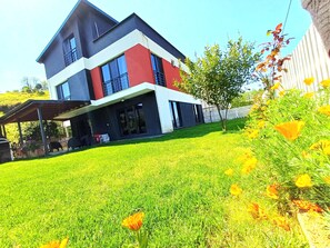 A modern two-story house with a covered patio and a well-maintained lawn.