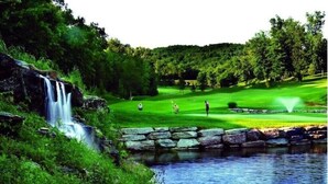 Un parcours de golf agrémenté d’une cascade, d’un étang et d’un pont en pierre.