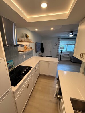 A modern kitchen with white cabinetry, a black stove, and a built-in oven.