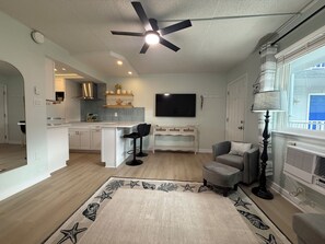 A modern kitchen with white cabinets, a central island, and a ceiling fan.