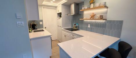 A modern kitchen with white cabinetry, a built-in stove, and a countertop island.