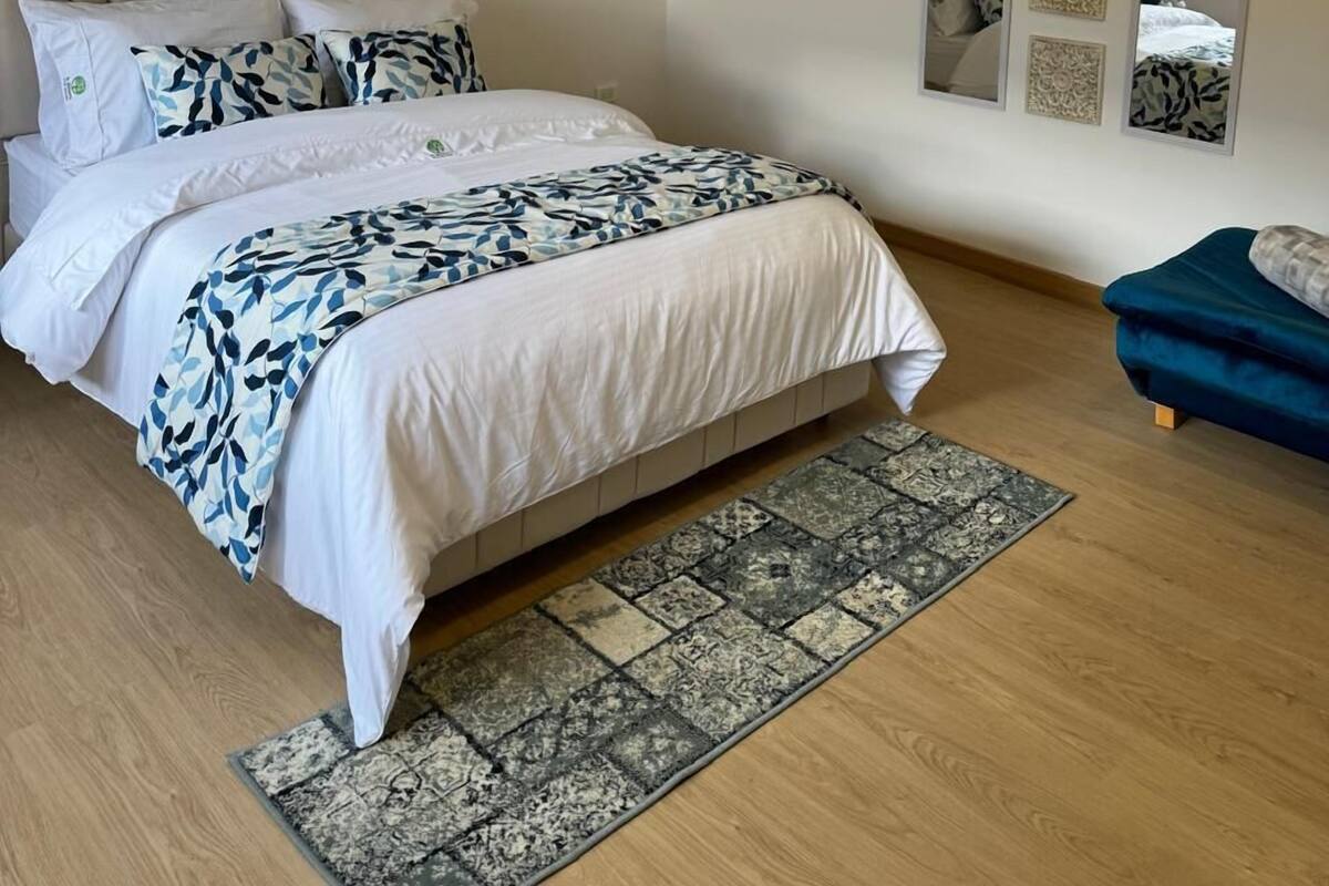 Een slaapkamer met een bed, nachtkastje, spiegel en een zithoek.