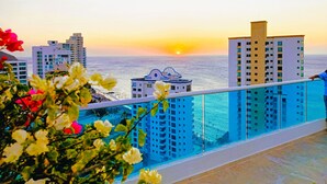 Un balcon avec vue sur la mer et les bâtiments au coucher du soleil.