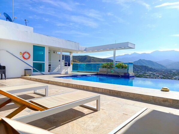 A modern outdoor pool area with a clear view of mountains in the background.