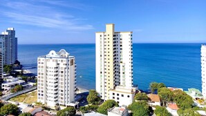 Un paysage urbain côtier avec de hauts immeubles, un ciel bleu dégagé et une vue sur la mer.