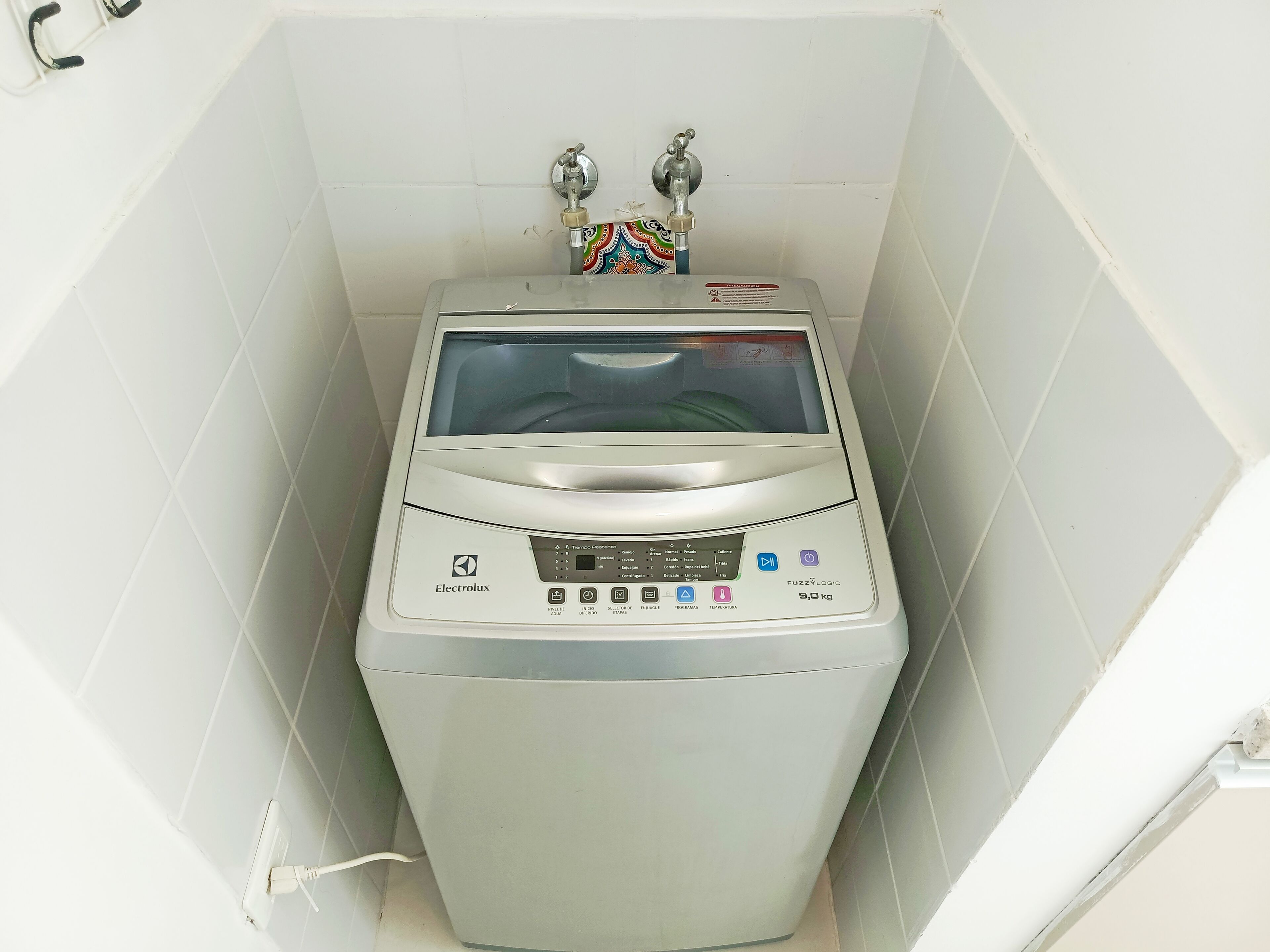 A compact, white, wall-mounted washing machine with a digital display and multiple control buttons.