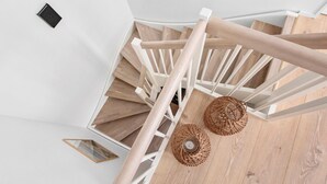 A wooden staircase with white railings, two woven floor lamps, and a framed picture on the wall. - 3 bedroom nice home in Løkken (Løkken)