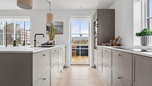A modern kitchen with a large island, grey cabinetry, and a view to the outdoors. - 3 bedroom nice home in Løkken (Løkken)