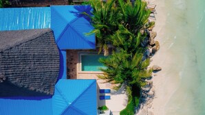 Oversigtsbillede af et resort med pool, blå parasoller og en strand.