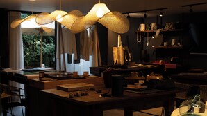 A modern interior with a dining area, a white pedestal table, and a large window with curtains. - Sui Posada Boutique (Medellín)