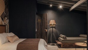 A modern bedroom with a bed, a sofa, a lamp, and a door. - Sui Posada Boutique (Medellín)