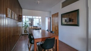 Ein Essbereich mit Holztisch und Stühlen, einer Topfpflanze und einem Fenster mit Tageslicht.