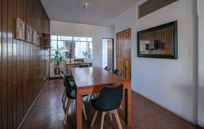 Ein Essbereich mit Holztisch und Stühlen, einer Topfpflanze und einem Fenster mit Tageslicht.