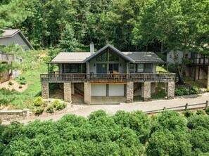A two-story house with a stone foundation, a covered deck, and a garage.