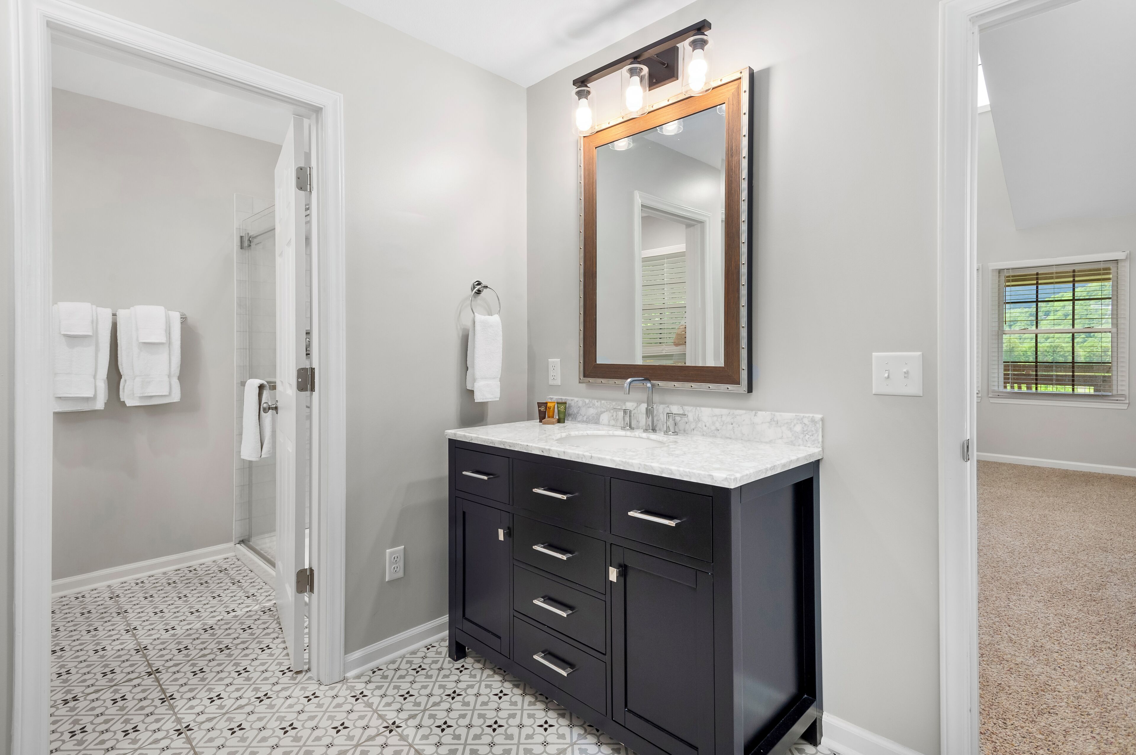 Une salle de bain avec un meuble-lavabo, un grand miroir et une douche.