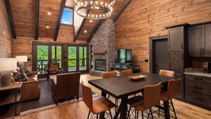 A spacious living area with a stone fireplace, wooden ceiling beams, and a large dining table with chairs. - Springdale Resort (Canton)