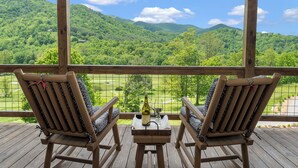 A wooden deck with two chairs facing a scenic view of green hills and a clear sky. - Springdale Resort (Canton)