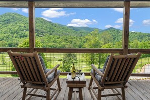 Relax on the deck with a scenic view of lush hills and a clear sky, surrounded by a safe and intimate setting.