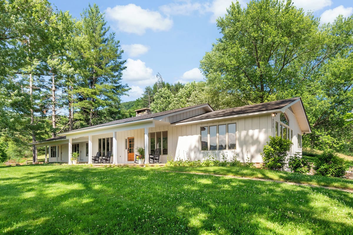 A single-story house with a covered porch, large windows, and a well-maintained lawn.