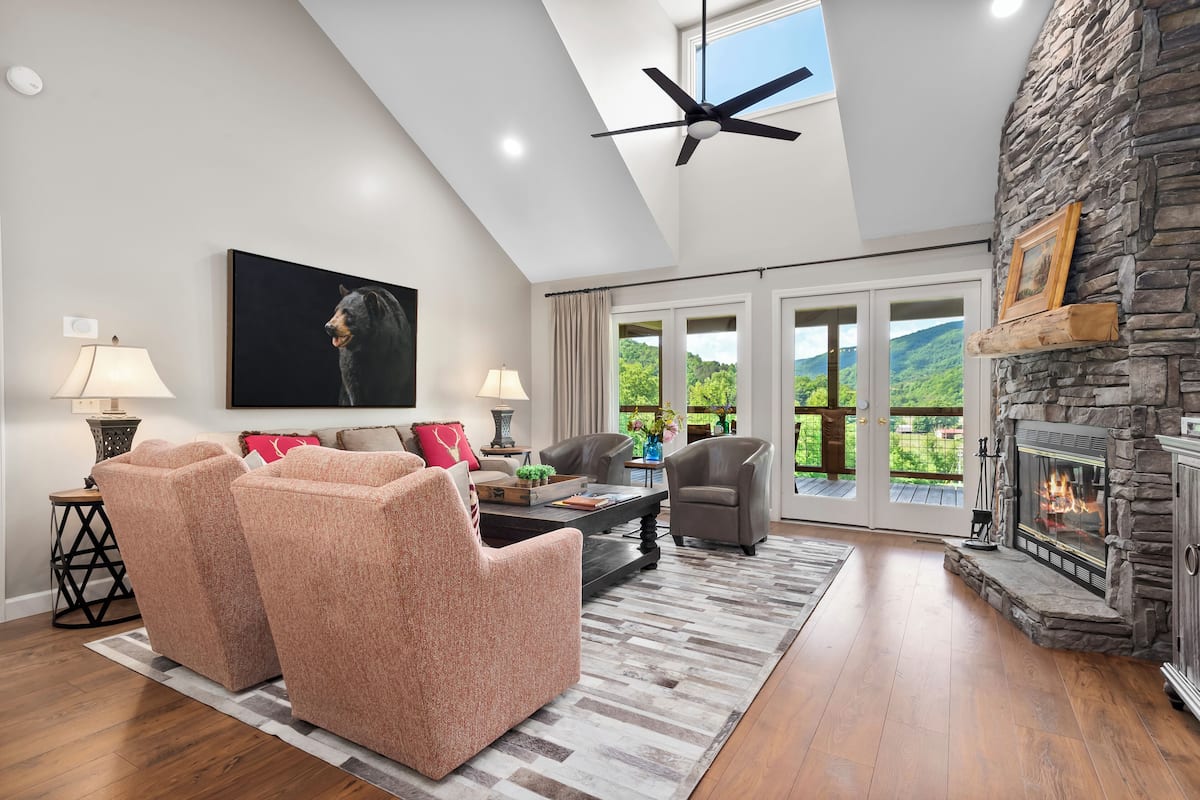 A spacious living room with a fireplace, comfortable seating, and a large window offering a scenic view.