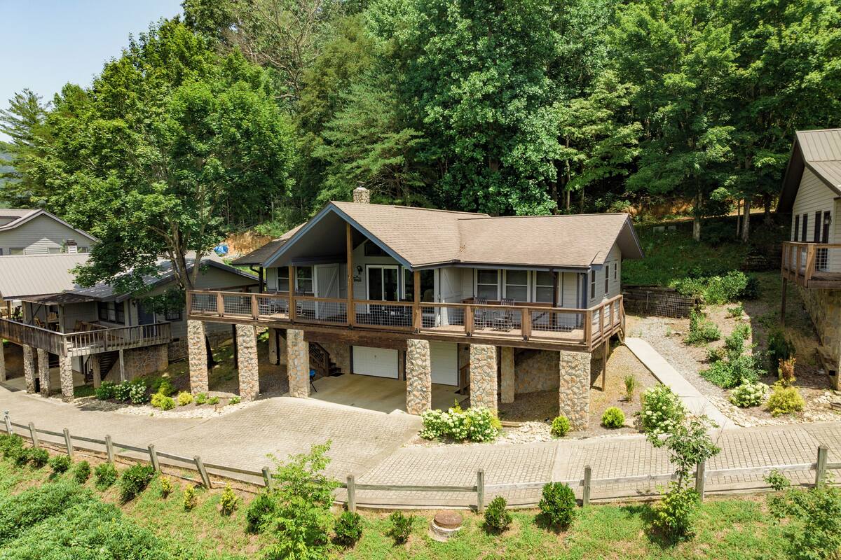A two-story house with a balcony, stone foundation, and a garage.