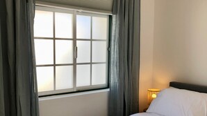 Une chambre à coucher avec un lit, des rideaux, une fenêtre et une lampe de chevet.