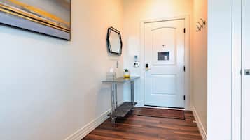 A hallway with a white door, a small table with a vase and a candle, and a painting on the wall.