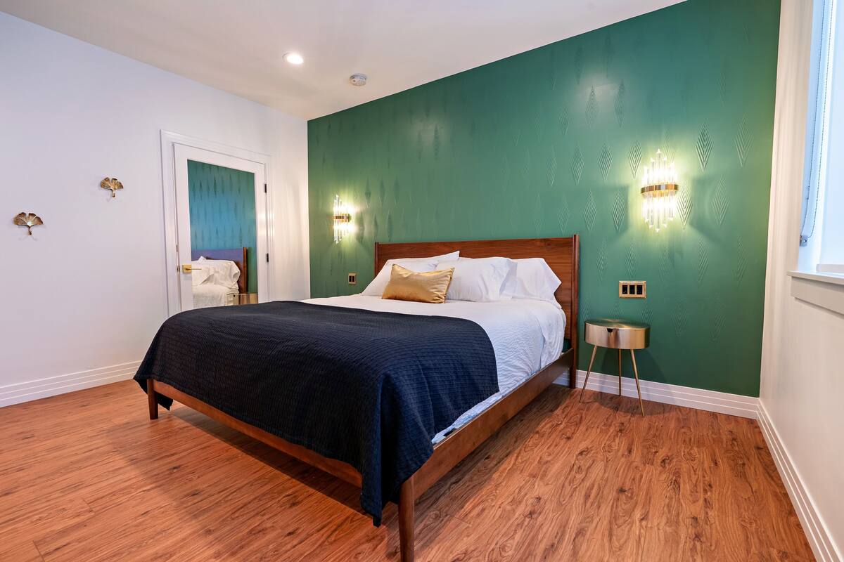 A bedroom with a wooden bed, green walls, and a small bedside table.