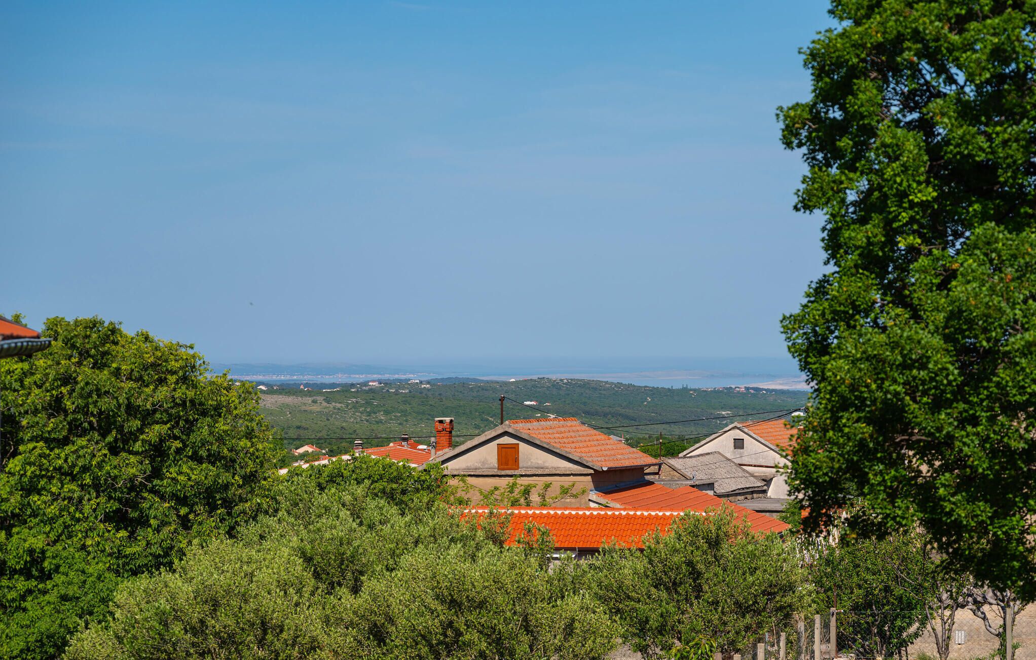 Vue d’un village côtier aux toits rouges traditionnels, entouré d’une végétation luxuriante et dominant la mer.