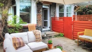 Une terrasse avec un canapé blanc, une table en bois et une clôture rouge.